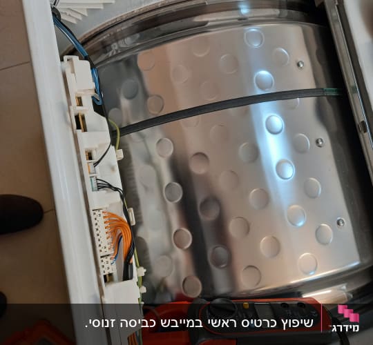 מולטימטר על מכונת כביסה פתוחה עם חוטים חשמליים